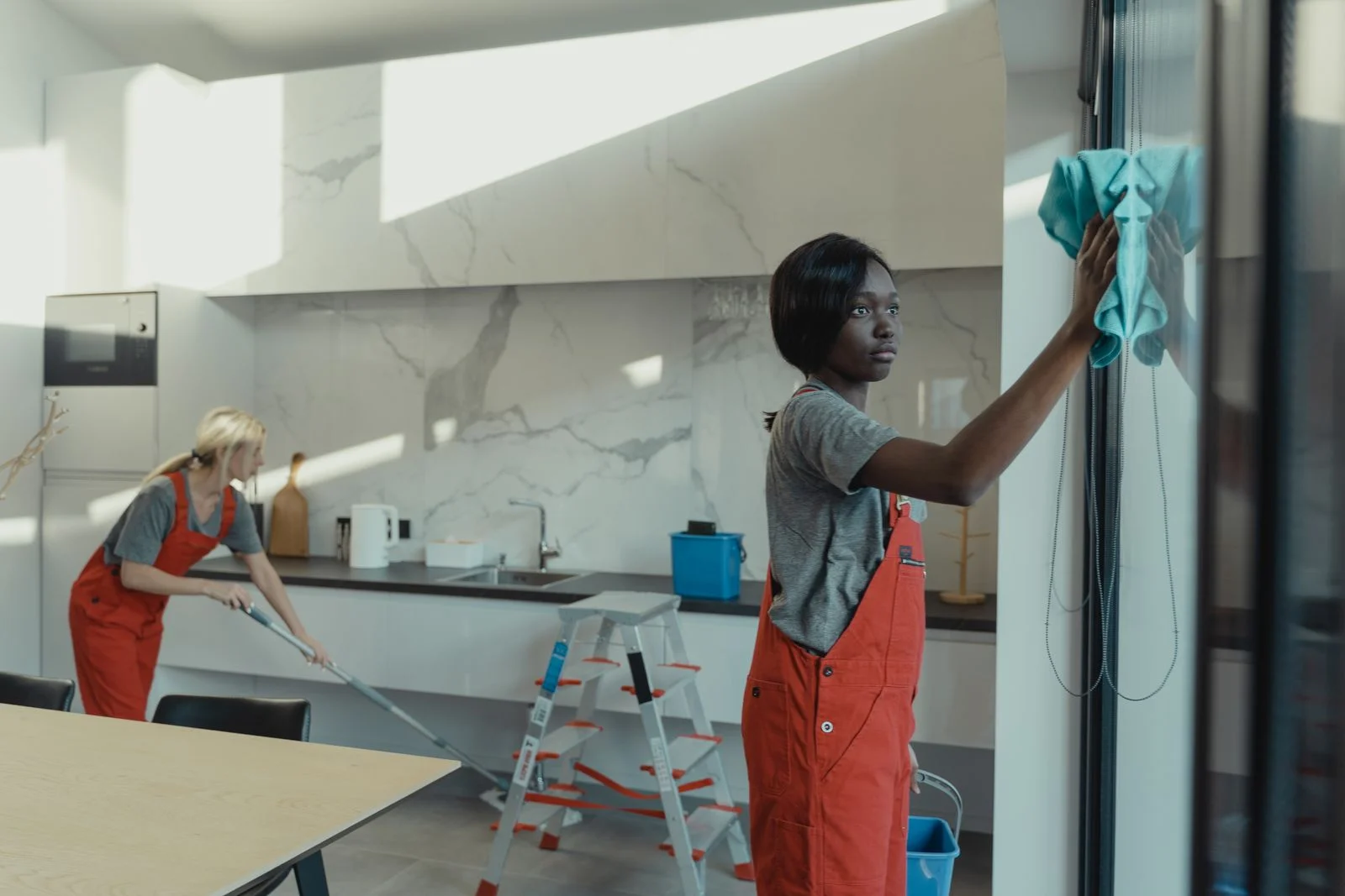Two cleaners giving a kitchen careful attention